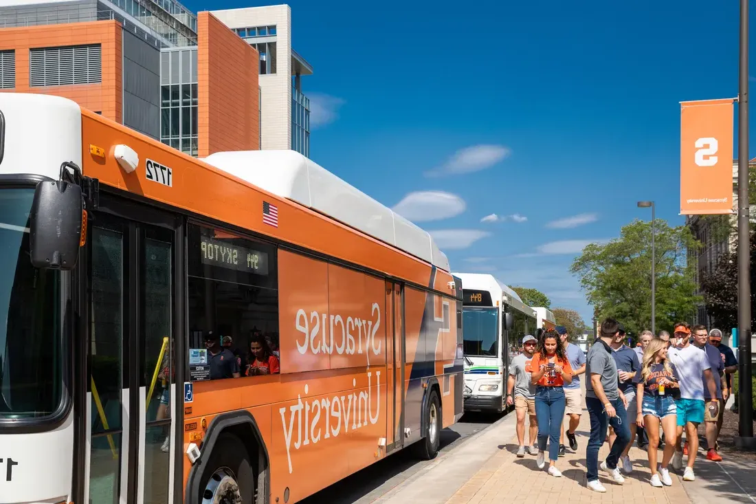 People getting off a bus on campus.